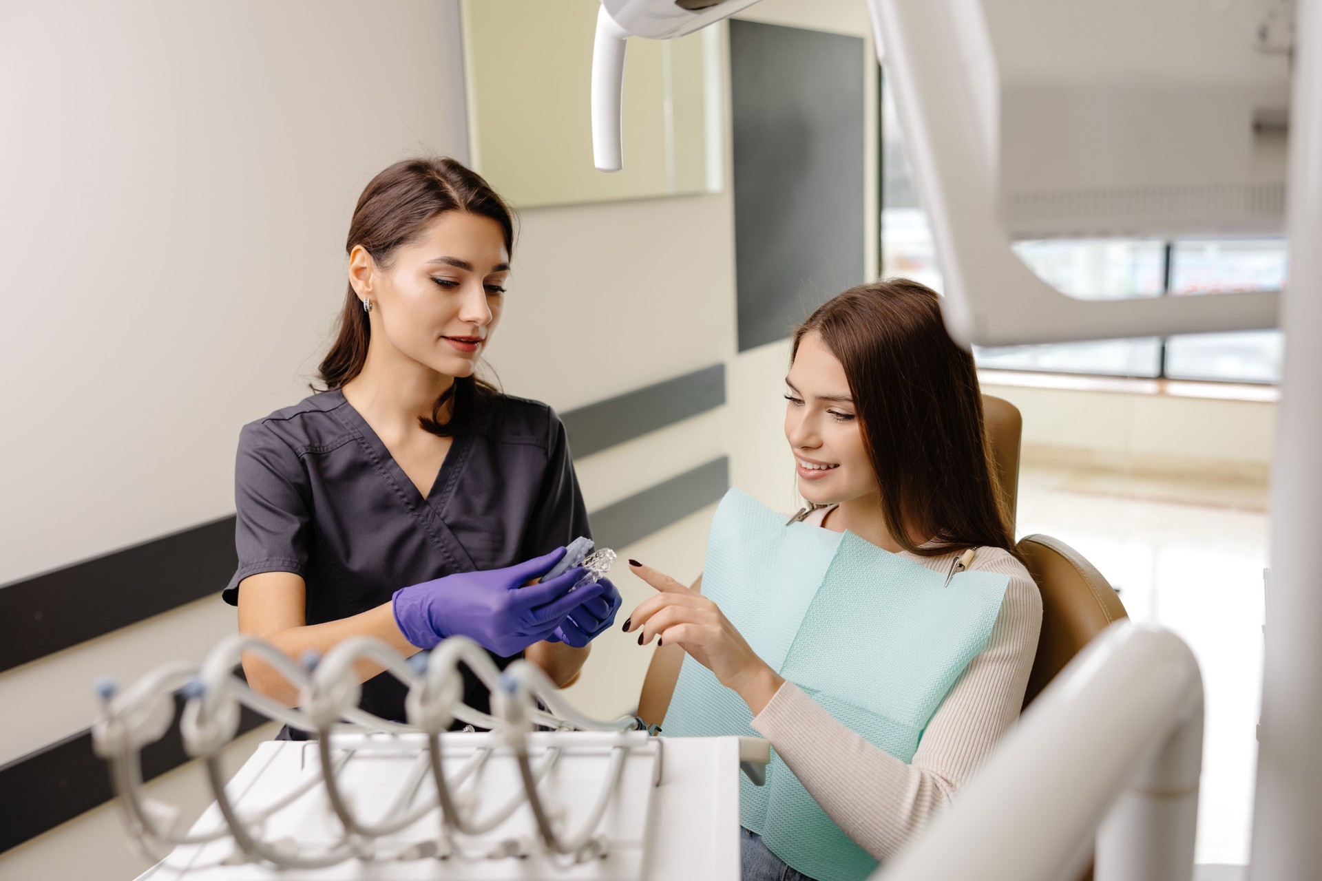 Dentist wearing rubber gloves holding transparent aligners for teeth correction for a patient in dentistry clinic