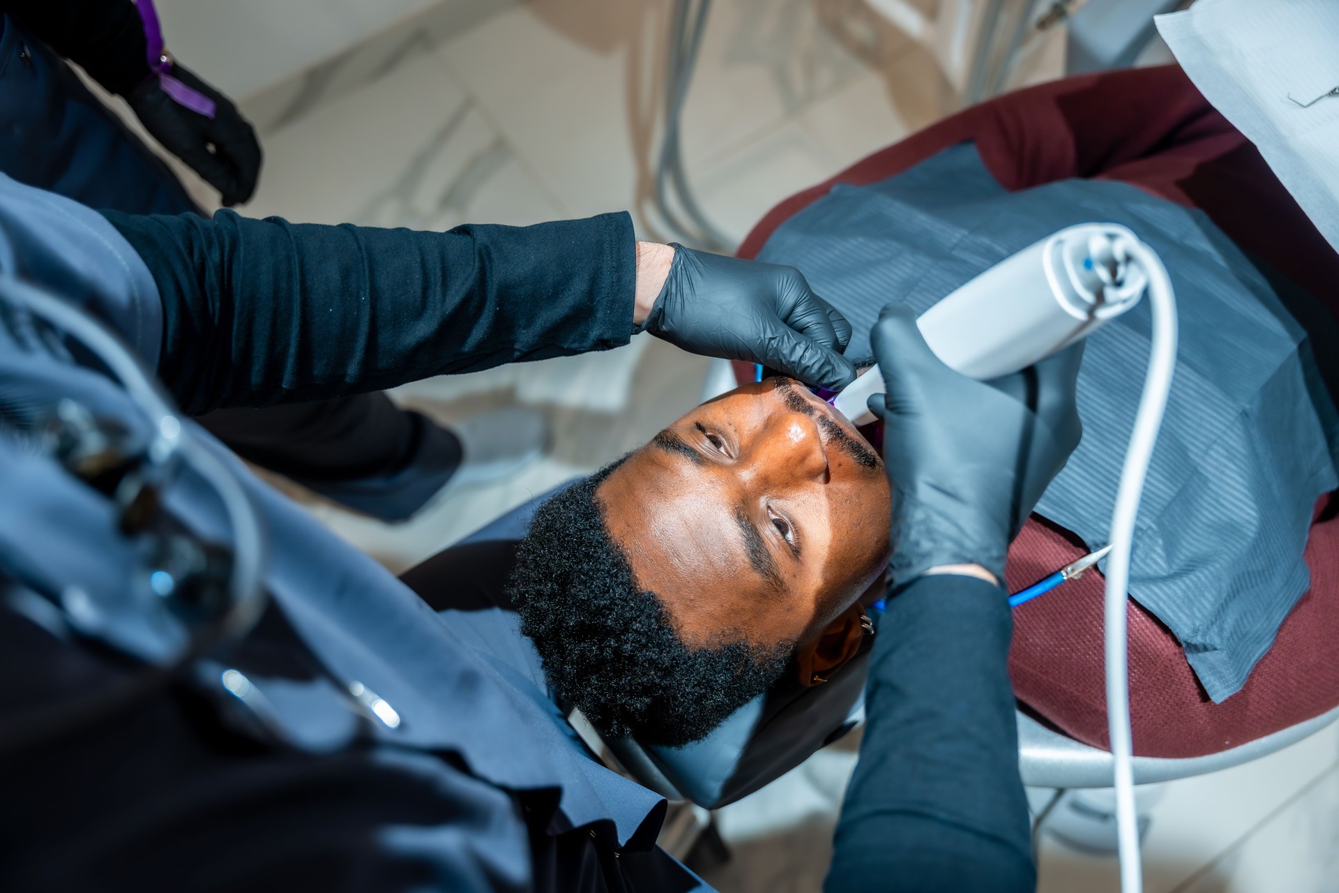 Dentist performing teeth whitening procedure on patient in modern clinic